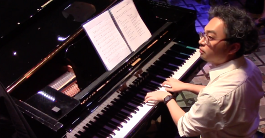 Thomas Cheng 正在彈奏鋼琴,展示其 London College of Music ALCM 爵士鋼琴演奏級及 Berklee 專業資歷。他是 Mother-Tongue Jazz Method 創始人。